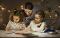 Portrait of mother interested in twins daughters evening activity at home