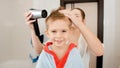 Portrait of mother and little boy drying hair with hairdryer after having bath. Concept of child hygiene and health care Royalty Free Stock Photo