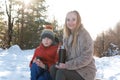 Portrait of mother and son snowy in forest drinking hot tea from thermos. Winter holidays