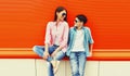 Portrait of mother with son teenager in sunglasses, checkered shirts on an orange background Royalty Free Stock Photo