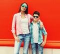 Portrait of mother with son teenager in sunglasses, checkered shirts on an orange background Royalty Free Stock Photo