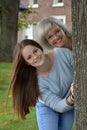 Portrait of mother and teenage daughter behind a tree Royalty Free Stock Photo