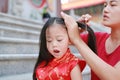 Portrait of Mother tying her daughter`s hair. Two tied ponytails hairs