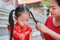 Portrait of Mother tying her daughter`s hair. Two tied ponytails hairs