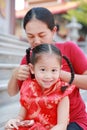 Portrait of Mother tying her daughter`s hair. Two tied ponytails hairs. Child girl looking at camera