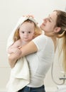 Portrait of young mother wiping her baby boy with big towel after having shower Royalty Free Stock Photo