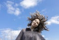 Portrait in motion of cheerful girl 18-19 years old with flying curly hair smiling looking at camera against blue sky Royalty Free Stock Photo