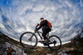 Portrait of the mountain cyclist standing with bike on the rocky hill against dramatic sky with clouds. Royalty Free Stock Photo