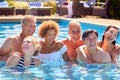 Portrait Of Multi-Cultural Group Of Senior Friends Relaxing In Outdoor Pool On Summer Vacation Royalty Free Stock Photo