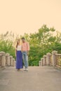 Full body shot of multi ethnic couple standing together and in love on the bridge of peaceful green park Royalty Free Stock Photo