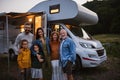 Portrait of multi-generation family looking at camera and smiling outdoors at dusk, caravan holiday trip. Royalty Free Stock Photo