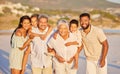 Portrait of a multi generation family on vacation standing together at the beach on a sunny day. Mixed race family with Royalty Free Stock Photo