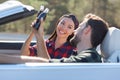 Portrait of multiethnic couple cheering with glass coke bottles riding the car Royalty Free Stock Photo