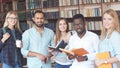 Portrait of multiethnic diverse friends pupils looking at page of interesting book in college library