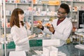 Portrait of multiethnical male and female pharmacists standing near pharmacy counter, talking, laughing and gesturing Royalty Free Stock Photo