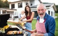 Portrait of multigeneration family outdoors on garden barbecue, grilling. Royalty Free Stock Photo