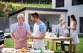 Portrait of multigeneration family outdoors on garden barbecue, grilling.