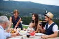 Portrait of multigeneration family sitting at table outdoors on garden barbecue.