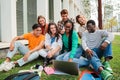 Portrait of multiracial college students using a laptop computer while having fun watching funny movie sitting on lawn Royalty Free Stock Photo