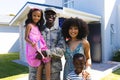 Portrait of multiracial smiling army soldier in camouflage clothing with family standing in yard