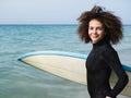 Portrait of a multiracial young surfer woman getting into the water Royalty Free Stock Photo