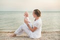 Portrait of mum and baby daughter on sandy shores of sea background. Happy mother and child