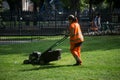 Portrait of municipal employee using lawn mower, shears lawns in urban park