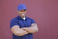 Portrait of a muscular African American delivery man with arms crossed over colored background Royalty Free Stock Photo