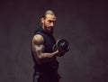 Portrait of a muscular bearded tattoed male with a stylish haircut wearing black sportswear, doing exercise with a Royalty Free Stock Photo