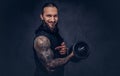 Portrait of a muscular bearded tattoed male with a stylish haircut wearing black sportswear, doing exercise with a Royalty Free Stock Photo