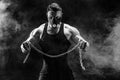 Portrait of muscular sportsman tearing metal chain. Black background with smoke Royalty Free Stock Photo