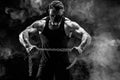 Portrait of muscular sportsman tearing metal chain. Black background with smoke Royalty Free Stock Photo