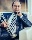 Portrait of a musician with a trumpet sitting in a chair, on the Royalty Free Stock Photo