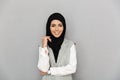 Portrait of muslim elegant woman 20s in hijab smiling and looking at camera, isolated over gray background Royalty Free Stock Photo