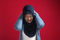 Portrait of muslim lady wearing red hijab having headache, migraine chronic head brain pain or stress mental pressure