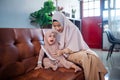 muslim Mother with hijab scarf comforting her crying little girl