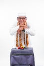 Portrait muslim old asian man with travel suitcase. going for ramadan eid mubarak celebration concept isolated over a white