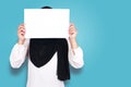 Portrait of muslim woman in hijab covering her face with blank empty paper. copy space mock up for anonymouse person Royalty Free Stock Photo