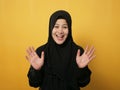 Muslim woman wearing hijab looking at camera smiling and waving her hands saying hi or goodbye farewell gesture against yellow Royalty Free Stock Photo