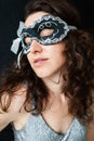 Portrait of a mysterious attractive woman in a carnival mask. Black background, lace mask on the face, shiny dress. Halloween Royalty Free Stock Photo