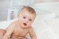 Portrait of naked smiling Infant sits on a bed in bedroom