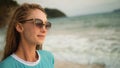 Natural beauty woman walking and relax on beach. Warm golden sunset. Woman with birthmark in blue swimsuit and