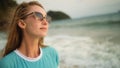 Natural beauty woman walking and relax on beach. Warm golden sunset. Woman with birthmark in blue swimsuit and