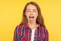 Portrait of naughty disobedient ginger girl in casual shirt standing with closed eyes and sticking out tongue, looking funny Royalty Free Stock Photo