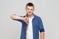 Teenager boy frowning angrily and showing thumbs down gesture, expressing disapproval, dislike. Royalty Free Stock Photo