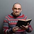 Portrait of a nerd holding book with retro glasses against gray background Royalty Free Stock Photo