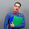 Portrait of a nerd holding books with retro glasses against gray background Royalty Free Stock Photo