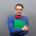 Portrait of a nerd holding books with retro glasses against gray background Royalty Free Stock Photo