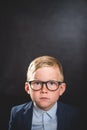 Portrait of nerd smart school child with thumb up near blackboard blank and looking at camera. Happy kid boy in uniform Royalty Free Stock Photo