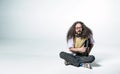 Portrait of a nerdy guy holding a briefcase and sitting on white floor Royalty Free Stock Photo